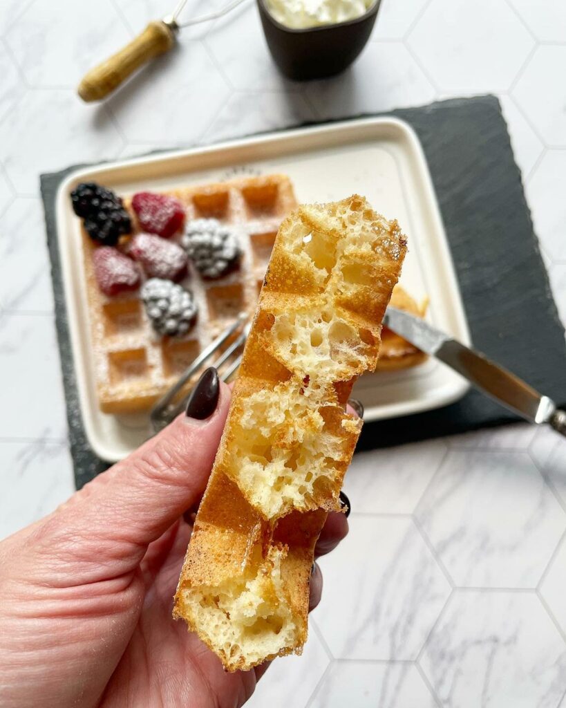 gaufre de Bruxelles coupée en deux et gaufre de Bruxelles avec fruits en arrière-plan.